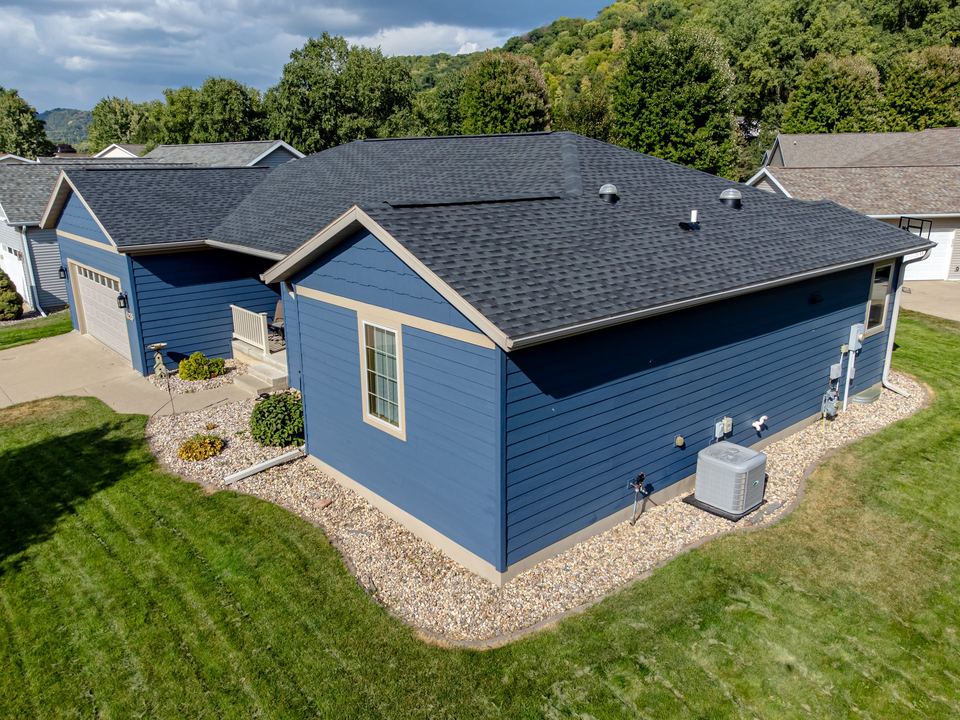 Aerial view of a blue house with fiber cement lap siding and white-trimmed windows