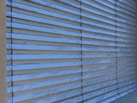 Close view of horizontal metal exterior slats dented by hailstones