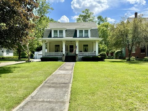White two-story house with lap siding, front porch and a long green lawn