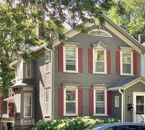 Gray lap-sided two-story house with red window shutters and white trim