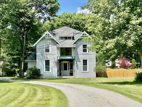 White two-story house with lap siding, gabled roof and a curving gravel driveway