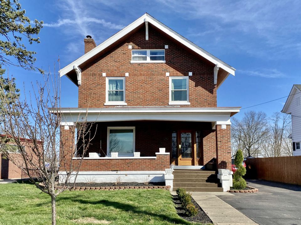 Red brick craftsman-style house with white trim, front porch and double-hung windows