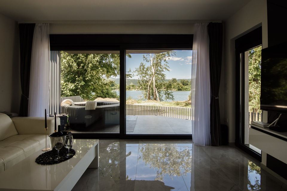 Bright modern living room with floor-to-ceiling sliding windows overlooking trees and water